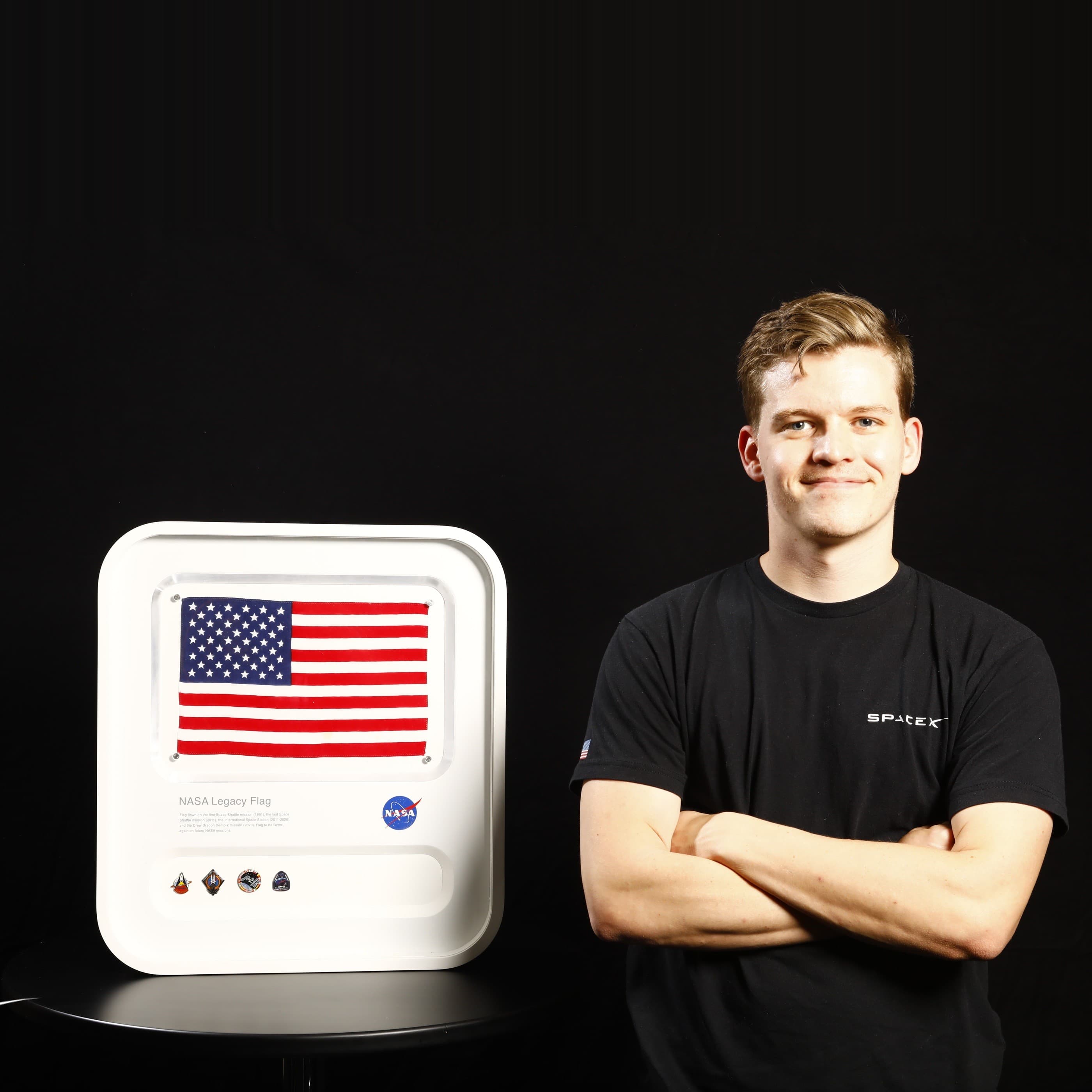 WarpKVM's founder beside the American flag that flew on multiple SpaceX Dragon missions
